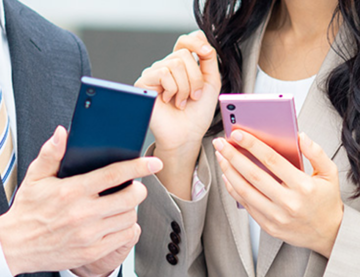 ビジネススーツを着た男性と女性が携帯電話を持っている